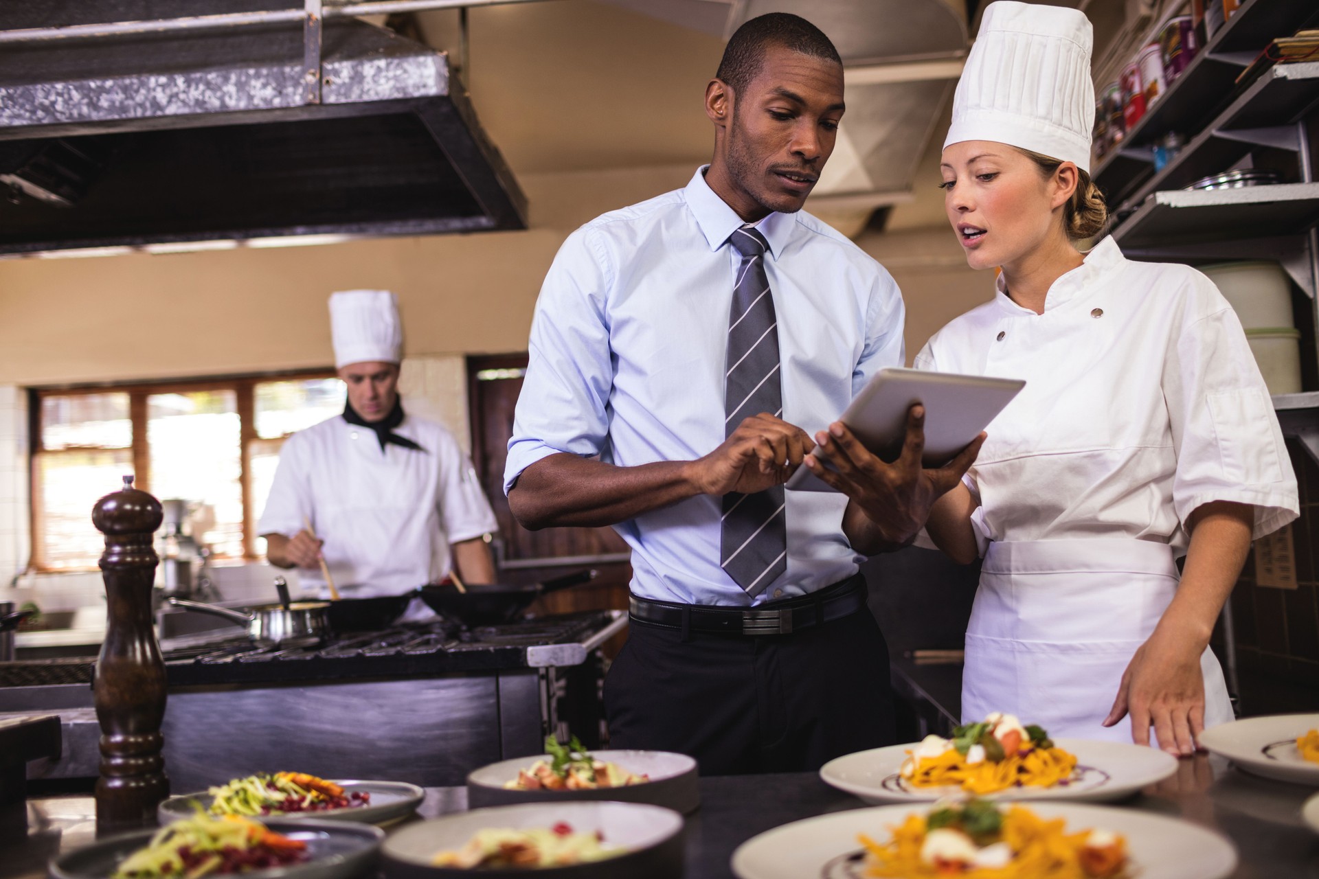 Male manager and female chef using digital tablet in kitchen